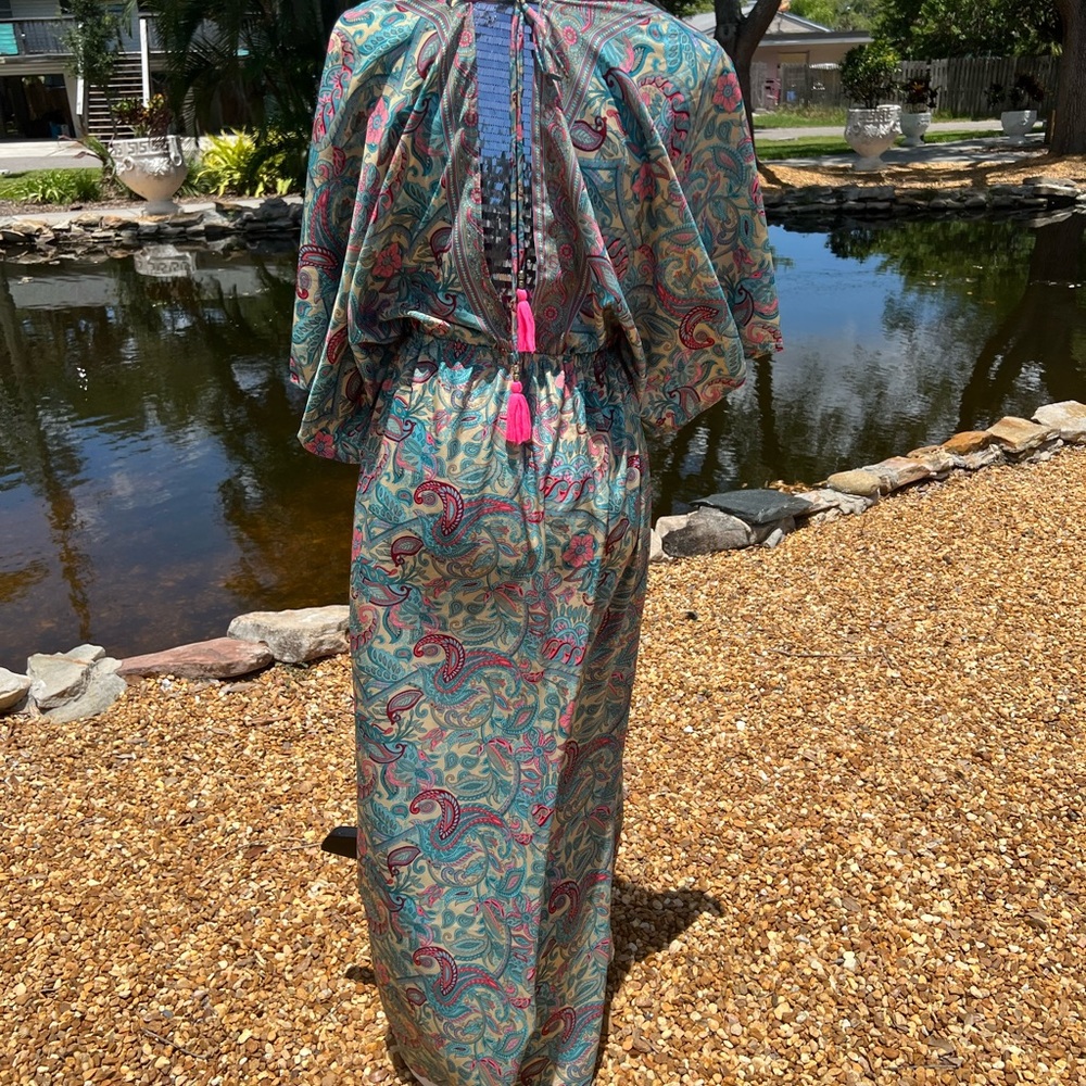 Deep V neck flowing paisley dress with bright pink tassels.